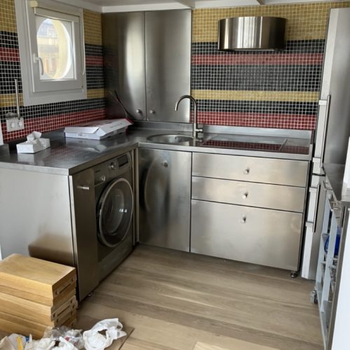 Cocina con muebles de acero inoxidable y azulejos coloridos en las paredes
