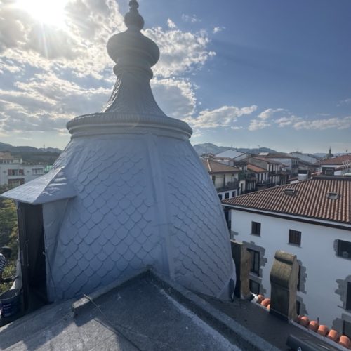 Cúpula de techo con tejas en rehabilitación y vista de urbanización