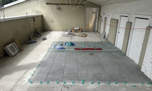 Suelo de cerámica en proceso de instalación con herramientas y materiales alrededor