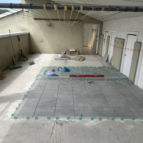 Suelo de cerámica en proceso de instalación con herramientas y materiales alrededor