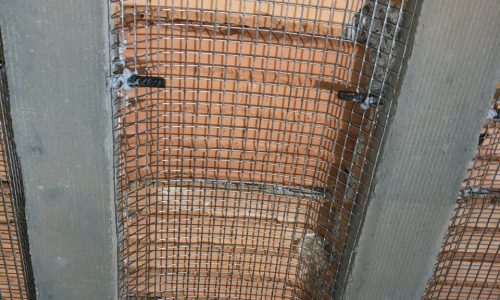 Malla de refuerzo metálica instalada en una pared de ladrillo