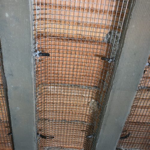 Malla de refuerzo metálica instalada en una pared de ladrillo