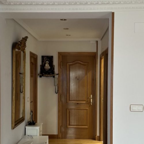 Pasillo con paredes pintadas y puertas de madera en una vivienda reformada